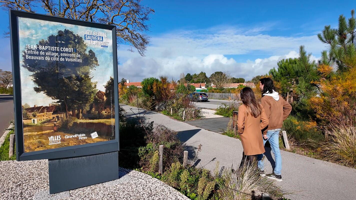 Photo d'un panneau publicitaire avec une oeuvre de l'initiative "La Beauté sauvera le monde" et deux personnes de dos