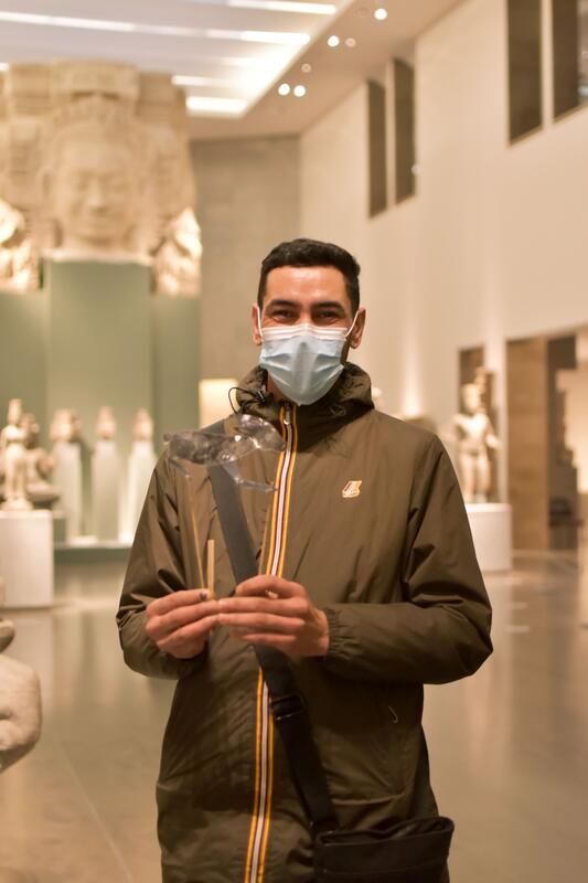 Brahimi pose avec sa marionnette dans le musée Guimet