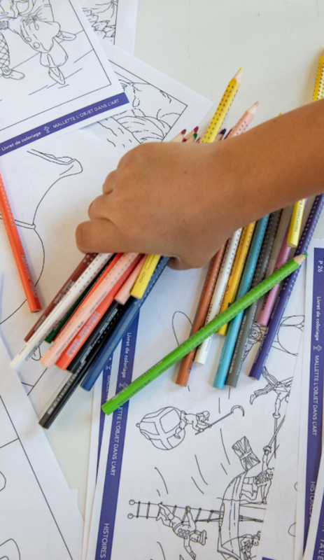 Une main d'enfant avec des crayons de couleurs et des dessins