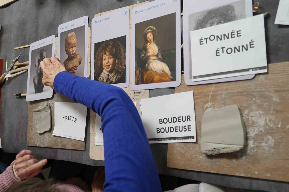 Les mains d'une personnes âgées jouant avec des cartes artistiques