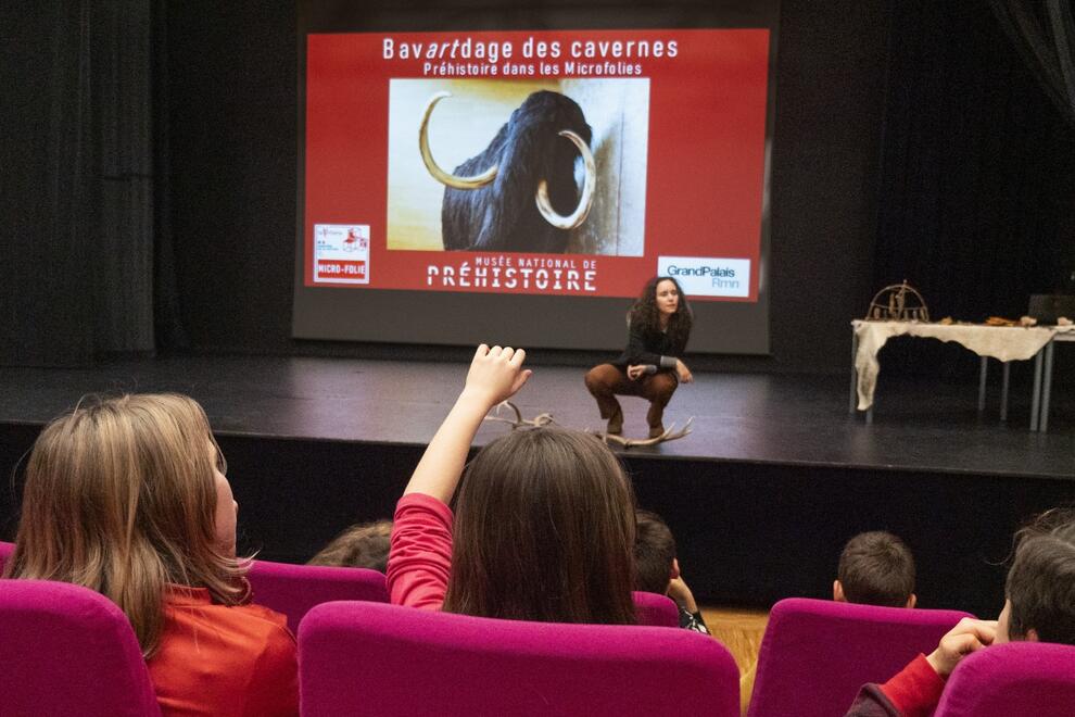 Des enfants assis dans un auditorium devant une présentation